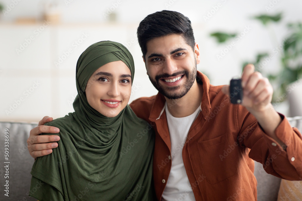 Cheerful Muslim Couple Showing New Car Key Sitting At Home