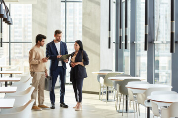 Minimal full length portrait of three business people talking in graphic white interior of office building, copy space
