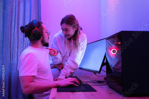 Young couple relaxing while playing video games on a personal computer in neon light © blackday