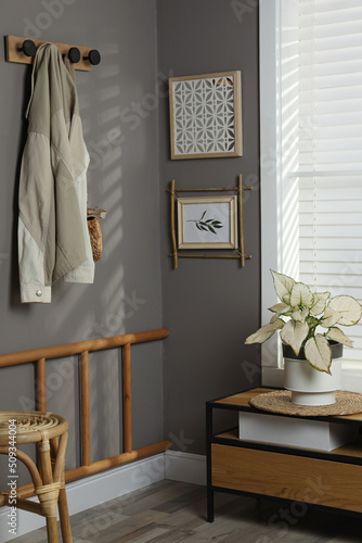 Stylish hallway interior with bamboo frame on grey wall