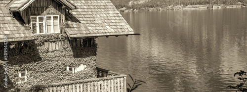 Print op canvas Wooden home along a mountain lake with vegetation on the walls.