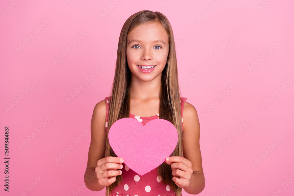 Portrait of positive adorable pupil arms hold paper card symbol toothy smile isolated on pink color background Portrait of positive adorable pupil arms hold paper card symbol toothy smile isolated on pink color background