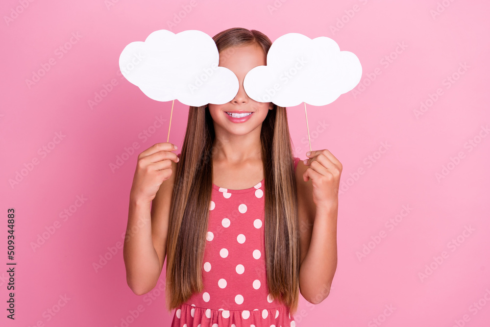 Photo of carefree excited small girl arms hold cloud paper cards cover eyes isolated on pink color background Photo of carefree excited small girl arms hold cloud paper cards cover eyes isolated on pink color background