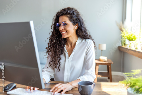 Shot of a young businesswoman working on a computer in an office. Portrait of an successful young creative businesswoman using PC at her workplace in the modern office photo