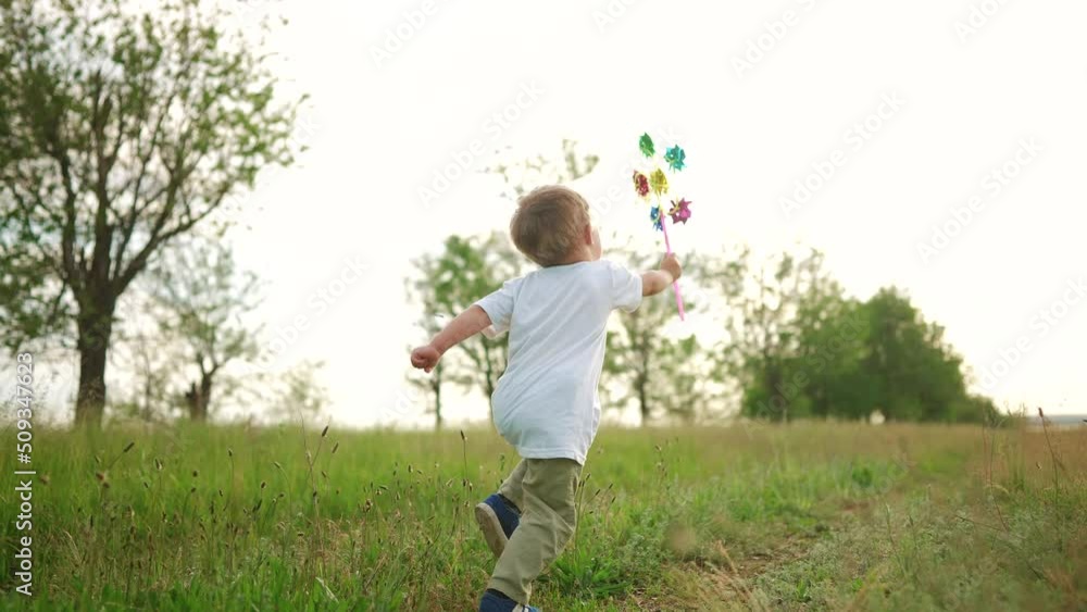 baby run play with a toy pinwheel windmill. happy family kid dream concept. kid run with a toy in the park close-up. happy childhood concept lifestyle. baby sunlight boy runs in the park in nature baby run play with a toy pinwheel windmill. happy family kid dream concept. kid run with a toy in the park close-up. happy childhood concept lifestyle. baby sunlight boy runs in the park in nature