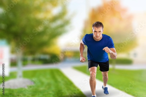 Young strong fitness man running in park