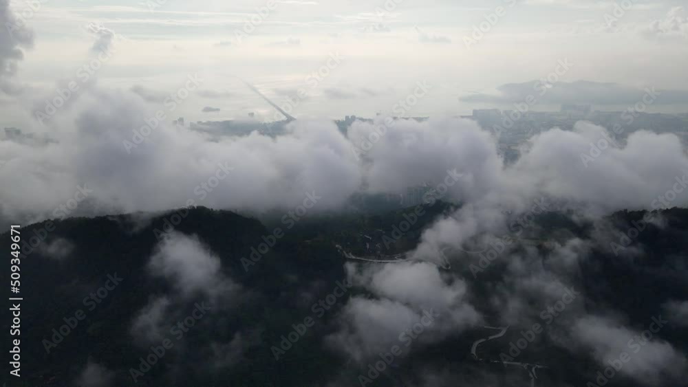 Aerial view foggy low cloud cover the hill. Background is Penang Bridge in misty day Aerial view foggy low cloud cover the hill. Background is Penang Bridge in misty day