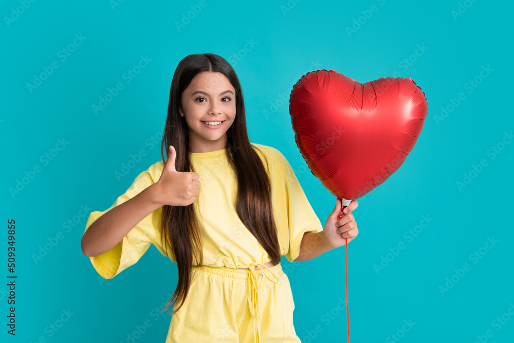 Beauty girl with red heart shaped air balloon over blue background. Beautiful teenager on birthday party, Love, Valentine's Day party. Happy girl face, positive and smiling emotions. Beauty girl with red heart shaped air balloon over blue background. Beautiful teenager on birthday party, Love, Valentine's Day party. Happy girl face, positive and smiling emotions.