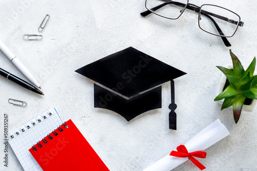 Students desk with graduation hat and diplima. Education concept photo