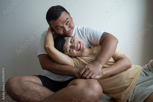 Asian guy couple smile and embracing together in the bed room.