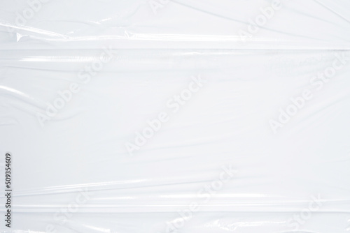 Transparent plastic wrap on white color background. Crumpled wrinkled plastic cellophane. Reflecting light and shadow on creases and folds in plastic surface. Texture overlay effect template