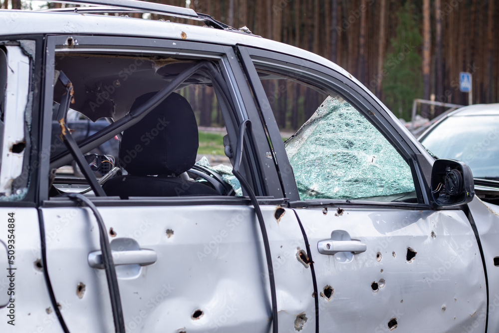 Fototapeta premium Car riddled with bullets. War of Russia against Ukraine. A car of civilians shot by the Russian military during the evacuation of women and children. Traces of bullets and fragments of shells.