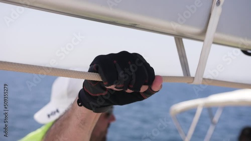 Gloved hand holds the rope on the yacht. 