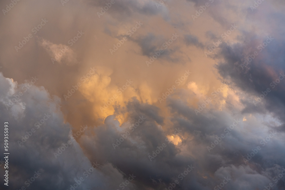 Fototapeta premium scenic view of thunderstorm building cumulus clouds with orange sunlight.