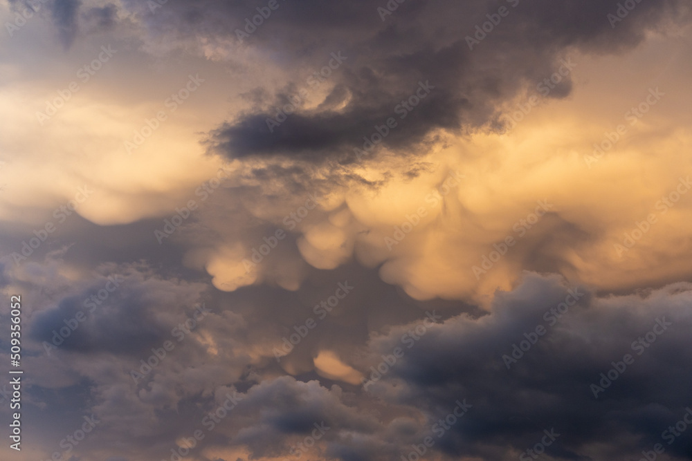 scenic view of thunderstorm building cumulus clouds with orange sunlight.