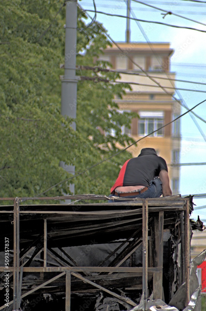 A man disassembles a burnt-out shopping kiosk on a summer day A man disassembles a burnt-out shopping kiosk on a summer day