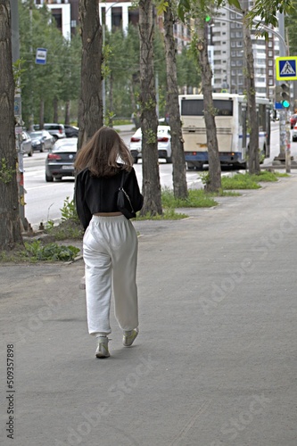 A woman walks along the sidewalk on a summer day