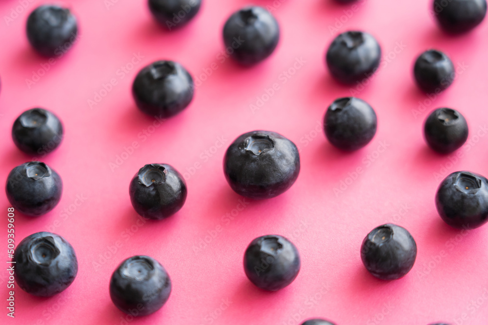 Close up view of fresh blueberries on pink surface.