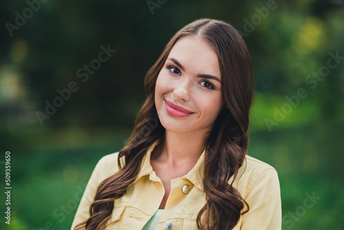 Portrait of attractive cheerful brown-haired girl spending time outside breathing fresh oxygen outdoors