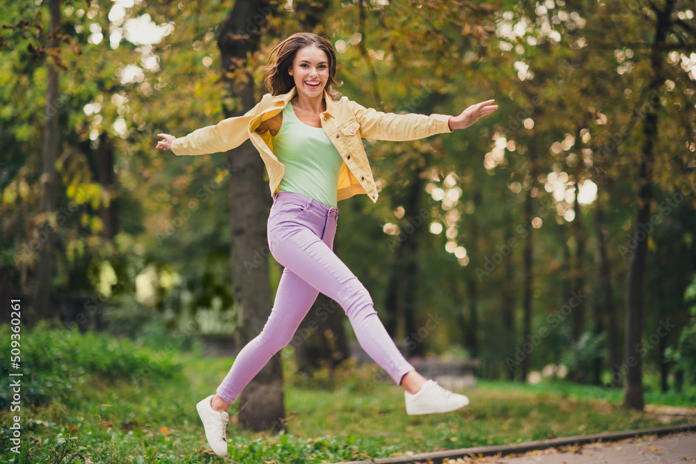 Full length body size view of attractive funky cheerful girl jumping having fun enjoying spending time outdoors Full length body size view of attractive funky cheerful girl jumping having fun enjoying spending time outdoors