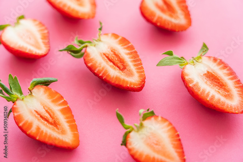 Close up view of cut strawberries on pink background.