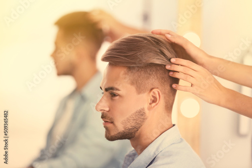 Professional hairdresser working with young man in barbershop