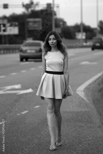Beautiful slim woman in dress at the road in black and white
