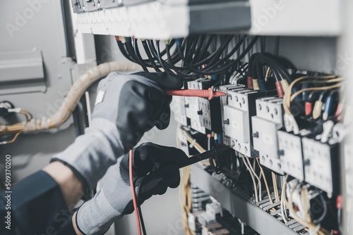 Electrician engineer tests electrical installations and wires on relay protection system. Adjustment of scheme of automation and control of electrical equipment. photo