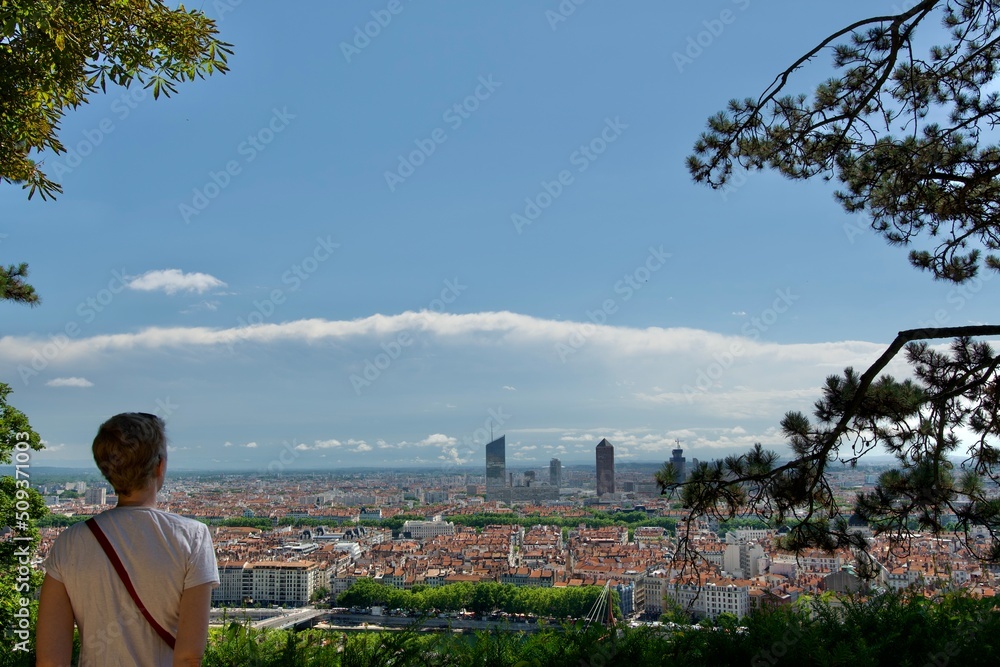 Pretty young woman, from back, admiring the view of lyon CBD, France