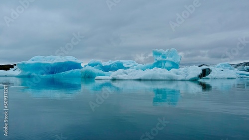 Gletscher Fjord und Gletscher Lagune. Kleine Eisstücke und riesige Eisberge - alles mit bewölktem Himmel.