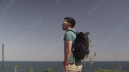 Caucasian male tourist delighting sea view in sunny summer weather during haikin on mountain trail. Hiking on Lycian way. Traveler with backpack stands on cliff. Adventure, travel people concept. photo