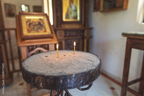 Candles burn in front of the iconostasis and the cross with a crucifix in a small chapel © berkut_34