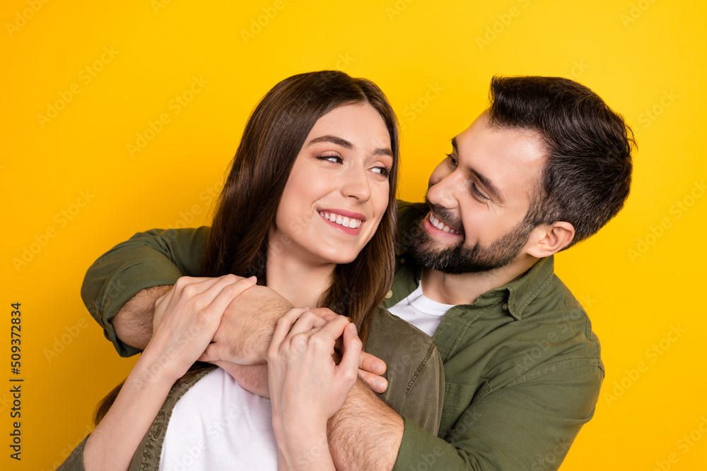 Portrait of two lovely positive people hug look each other isolated on yellow color background Portrait of two lovely positive people hug look each other isolated on yellow color background