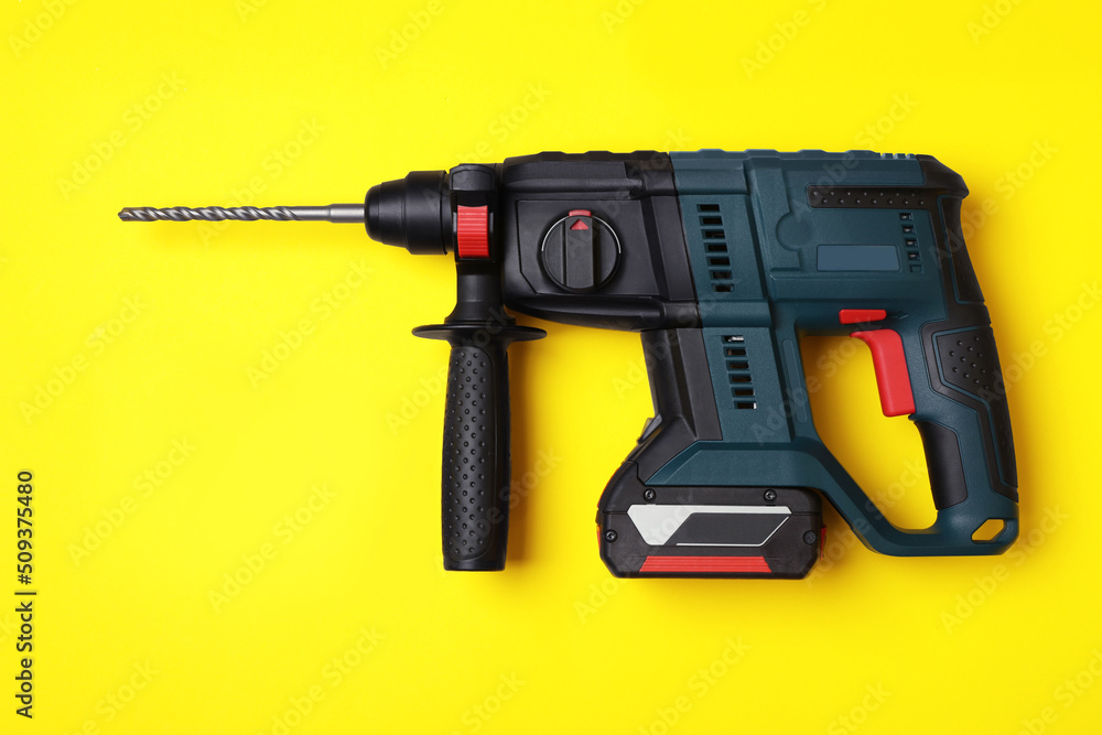 Modern electric power drill and different bits on yellow background, flat lay Modern electric power drill and different bits on yellow background, flat lay
