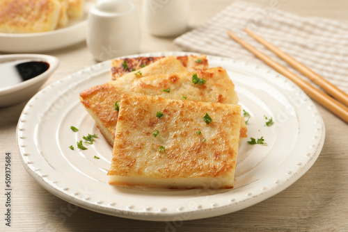 Delicious turnip cake with parsley served on wooden table, closeup