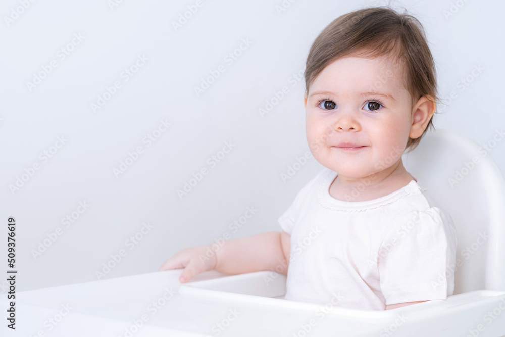 Portrait cute baby girl on kitchen sitting on high chair, smiling child happy to eat first solid food. Portrait cute baby girl on kitchen sitting on high chair, smiling child happy to eat first solid food.