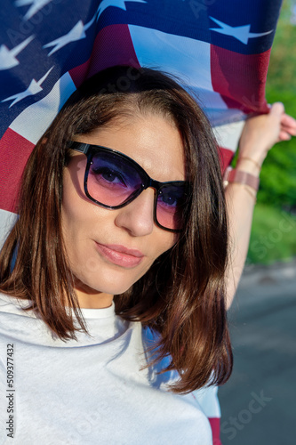 Young woman holding USA flag outdoors at sunset. Independence day.
