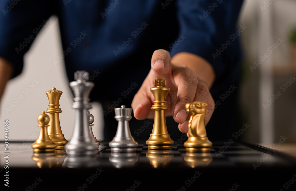 Close up of hands of a business man moving king golden chess to defeat  opponent the chess game is development analysis, strategy, and plan, the  management or leadership concept. 22804709 Stock Photo