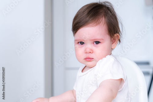 Fotografie portrait unhappy crying baby child sitting on highchair on kitchen at home, baby dont want to eat food