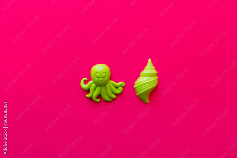 top view of green octopus and shellfish toys on pink background. top view of green octopus and shellfish toys on pink background.