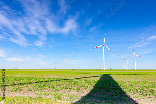Long shadow under windmill  large wind power turbines spinning to generating clean  green  renewable energy