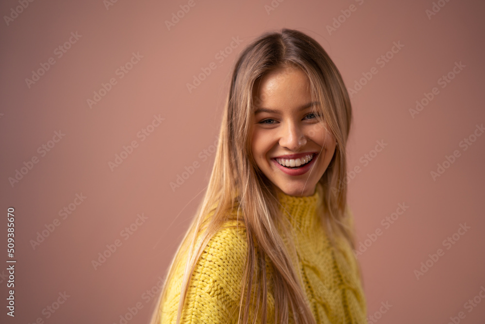 Fototapeta premium Fashion studio portrait of happy young blonde woman posing over pink background.