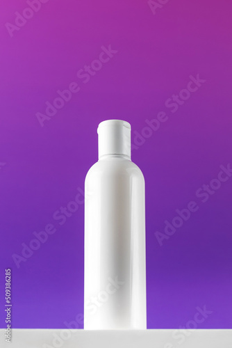 Blank bottle of mincellar water on purple background. Cleanness and refreshing procedures photo