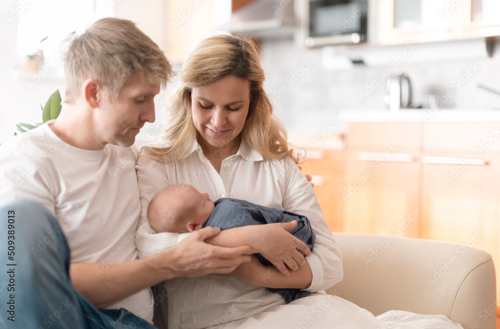Smiling mother and father holding their newborn baby daughter at home Smiling mother and father holding their newborn baby daughter at home