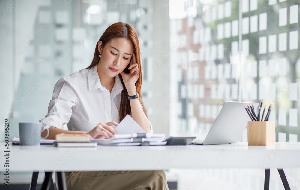 Portrait of happy young Asian woman celebrating success with arms up in front of a laptop at office Portrait of happy young Asian woman celebrating success with arms up in front of a laptop at office