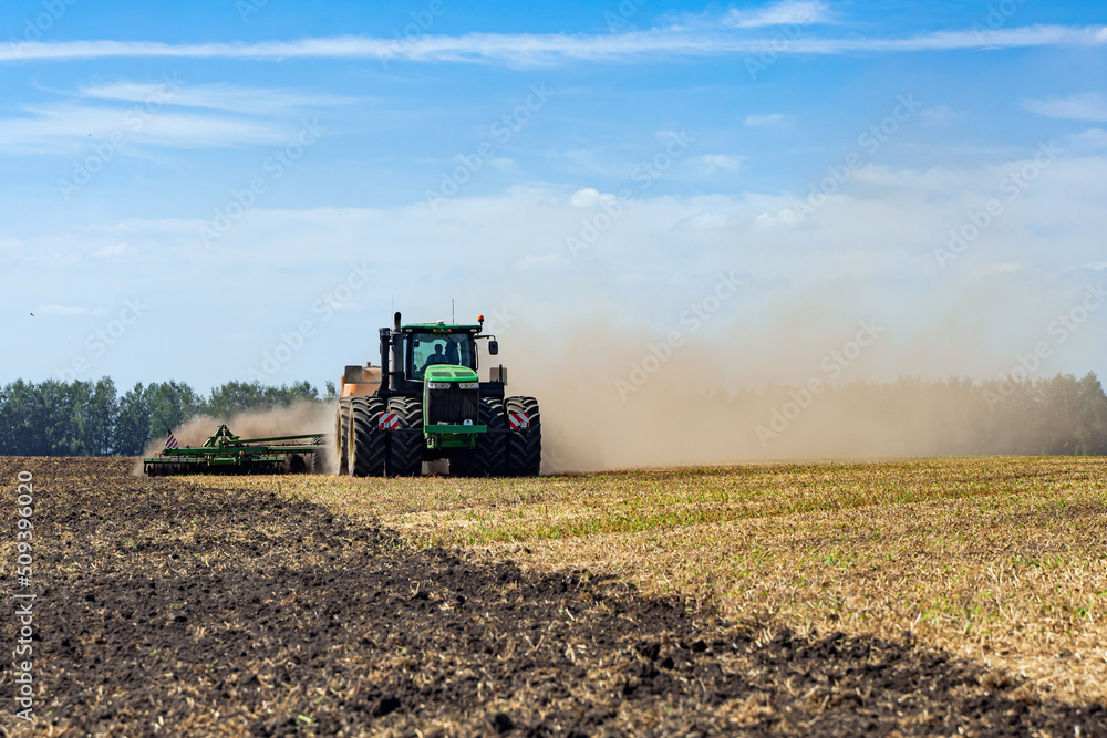 Fototapeta premium The tractor plows the land. Agriculture image.