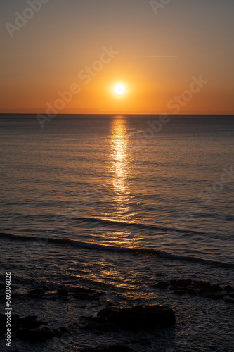 Sunset in calm waters of Atlantic ocean and clear sky