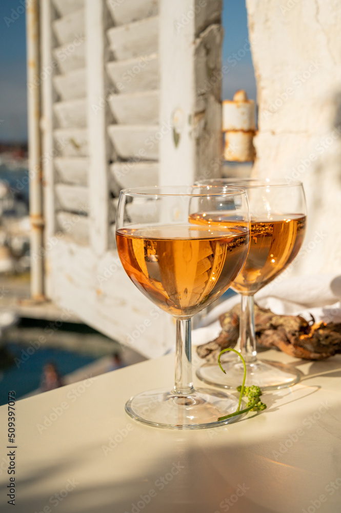 Summer party with cold rose wine in glass served on outdoor terrace in sunlights with view on old fisherman's harbour with colourful boats in Cassis, Provence, France Summer party with cold rose wine in glass served on outdoor terrace in sunlights with view on old fisherman's harbour with colourful boats in Cassis, Provence, France
