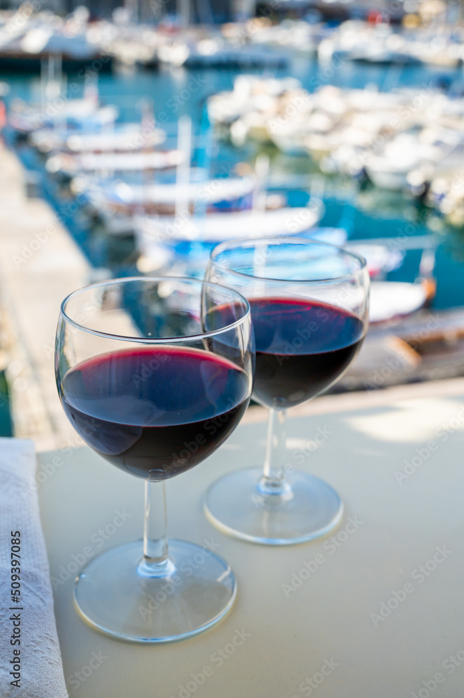 Drinking of red wine on outdoor terrace with view on old fisherman's harbour with colourful boats in Cassis, Provence, France