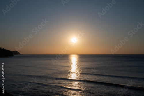 Sunset in calm waters of Atlantic ocean and clear sky